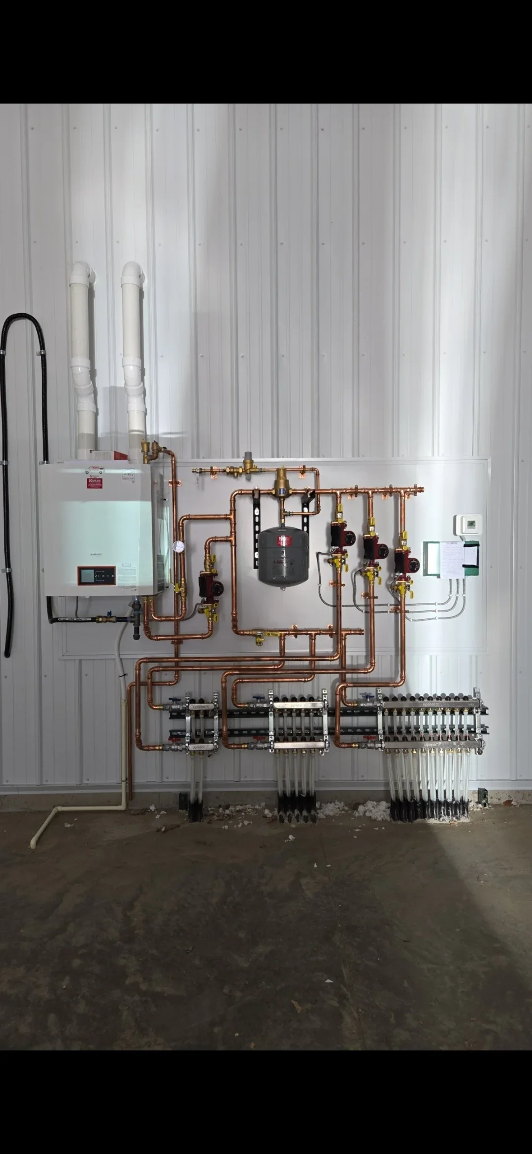 Tankless water heater with copper radiant heating manifold, expansion tank, and multi-zone distribution valves